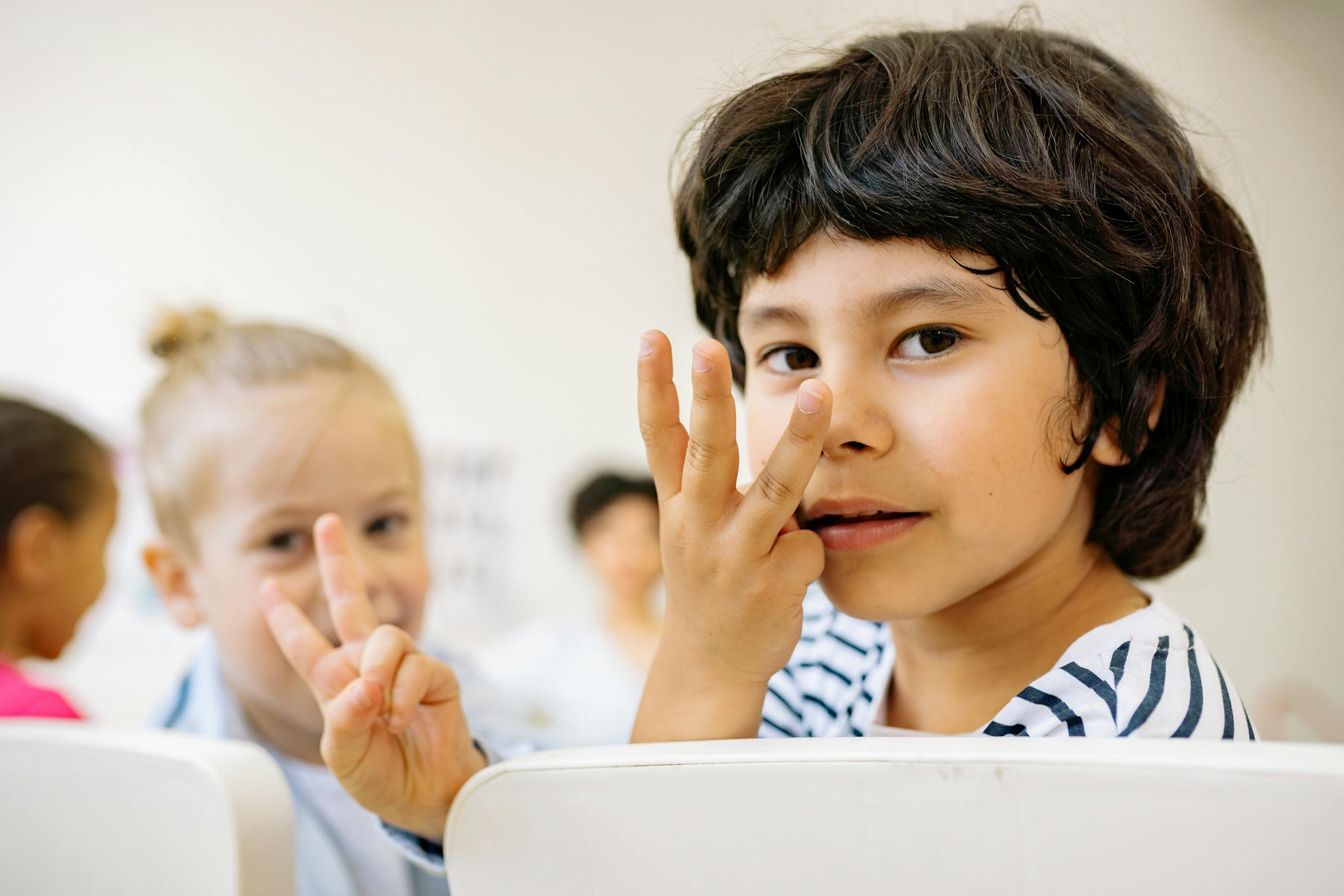 Children engaged in counting activity indoors with focus on learning and happiness.